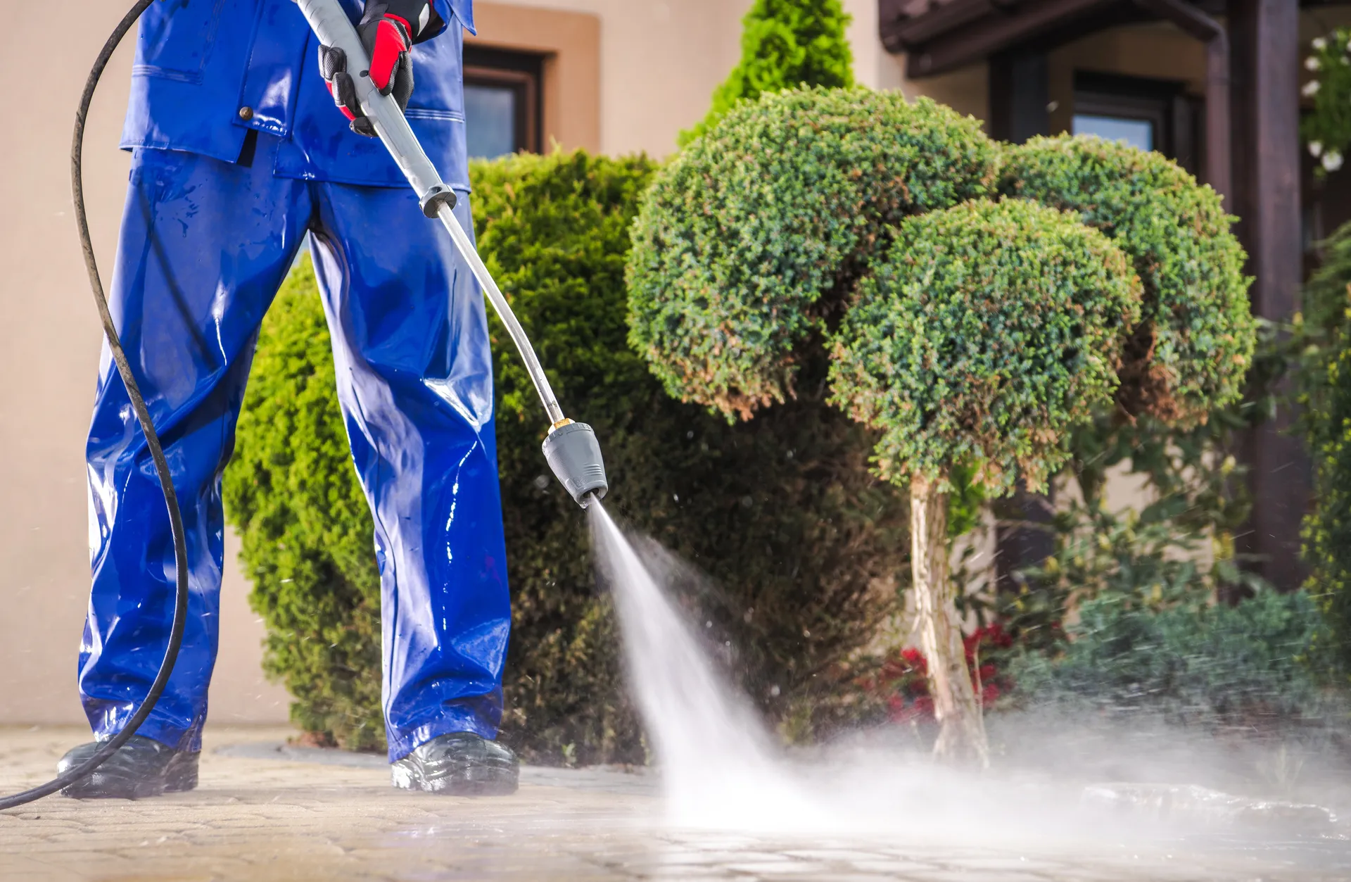 Peyton technician soft washing a patio beside trimmed shrubs